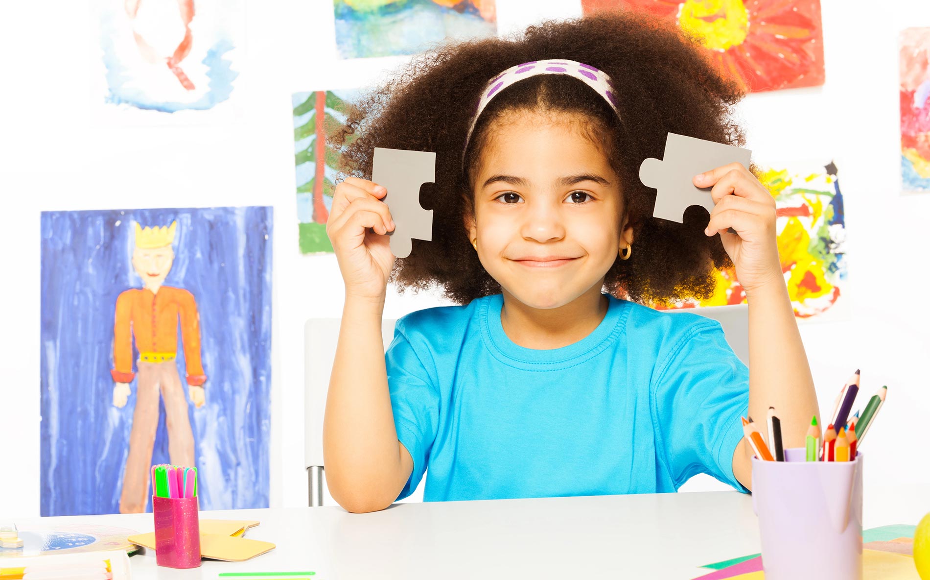 Smiling girl holding puzzle pieces.